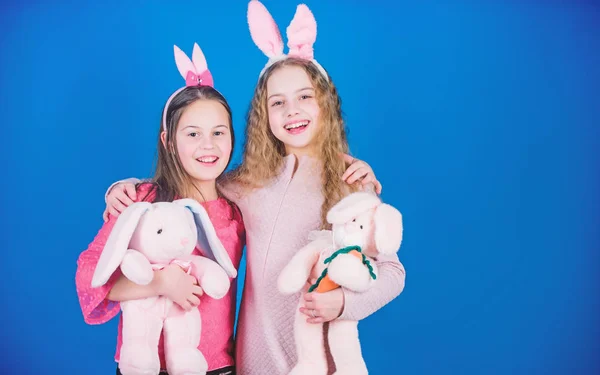 Kinderen met bunny speelgoed op blauwe achtergrond. Zusters glimlachend schattige bunny kostuums. Verspreiden van de vreugde en geluk rond. Hoop liefde en vreugdevol leven. Vrienden kleine meisjes met bunny oren Pasen vieren — Stockfoto