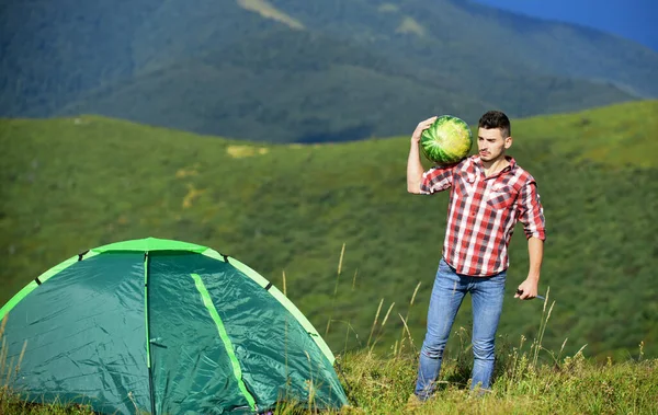 Túrázó és kempingsátor. Az ember görögdinnyét hoz a hegyekbe piknikezni. Nyári szünet. Kellemes kirándulás piknik. Gyümölcs egészséges étel. Kirándulás piknik. Kempingkoncepció. Piknik a hegyekben. Nyári kalandok — Stock Fotó