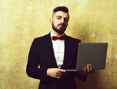 Şık görünümlü sakallı işadamı emin yüz ifadesi ile laptop tutar