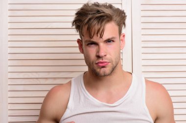 Bej jaluzinin arka planında tıraşsız yüzü olan adam.