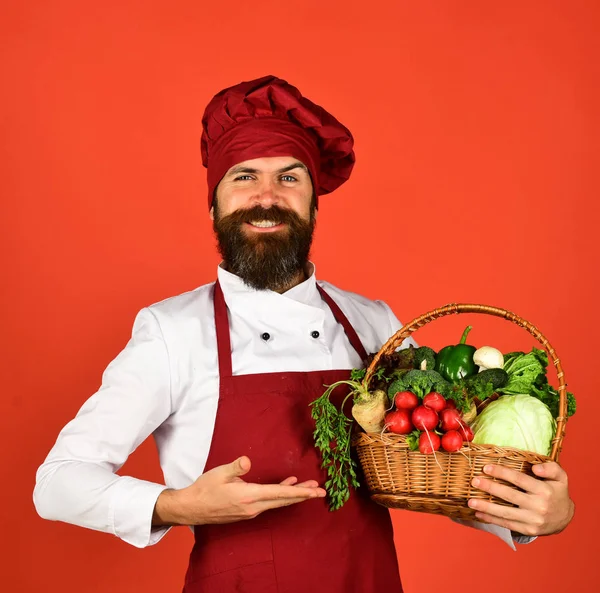 Mann mit Bart auf rotem Hintergrund. Koch hält Gemüse — Stockfoto