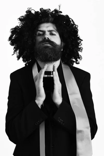 Caucasian hipster in suit and black curly wig holding perfume — Stock Photo, Image