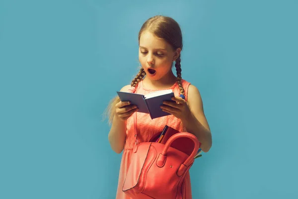 Chica con bolsa rosa lee libro azul. Regreso a la escuela — Foto de Stock