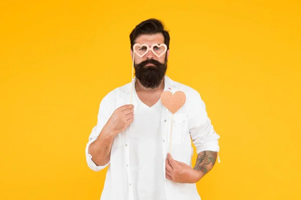 Hipster masculino grave em óculos de festa. homem barbudo hipster fundo amarelo. amor coração para feriado dia dos namorados. Feliz aniversário. Homem brutal com barba apaixonar-se. data romântica — Fotografia de Stock