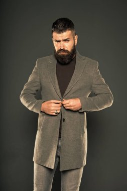 Onun tarzı için mükemmel trendy kıyafet seçimi. Acımasız hipster moda bıyık ve sakal saç stili giymek. Sakallı adam gri arka planda rahat tarzı ceket ilikleme. Her erkek için bir stil vardır.