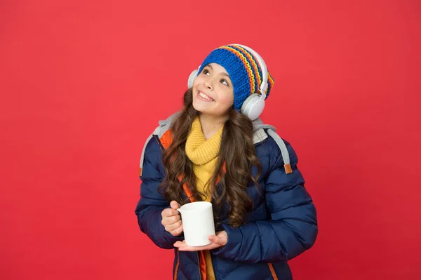 Listening music and drinking cocoa. Music taste. Weekend begins like that. Hipster fashion trend. Winter holidays activity. Feeling warm and happy. Cheerful smiling child stylish outfit listen music