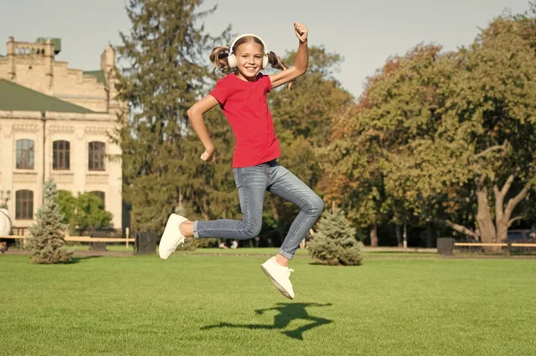 Driving dancer excellence. Little dancer perform leap on green grass. Cute girl dancer dancing energetic dance. Adorable small dancer jump to music playing in headphones