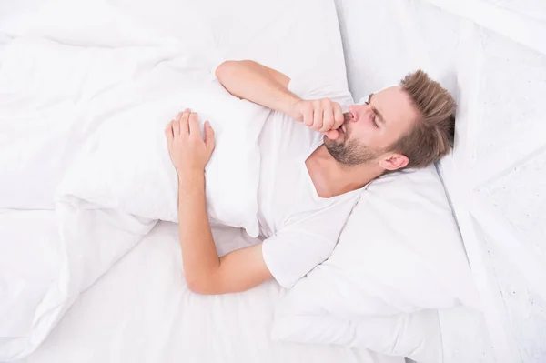 Hombre guapo relajándose en la cama. Los ronquidos pueden aumentar los dolores de cabeza de riesgo. Síntoma común de apnea del sueño. Causas de dolor de cabeza temprano en la mañana. Dolores de cabeza por migraña. Los problemas para dormir pueden provocar dolores de cabeza por la mañana. —  Fotos de Stock