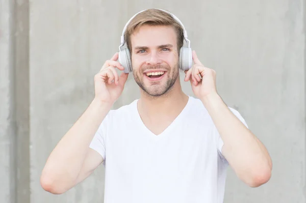 Trådlös hörlur. Snygg kille bär hörlurar grå bakgrund. Man lyssnar på modern musik. Modern teknik. Hobby fritid. Vikbara stereohörlurar. Bullerminskning. Modern och modern musik — Stockfoto