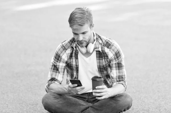 Bienestar y salud. Tomando un café. El hombre se sienta en el suelo mientras bebe café. Relájate y recarga. Diviértete durante el descanso. Guy estudiante despreocupado disfrutar del café al aire libre. Vida universitaria. Balance de vida — Foto de Stock