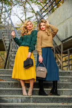 Süveter etek modası. Birbirimizi tamamlıyoruz. Vogue konsepti. Sarışın kızlar aynı kıyafetleri giyer. Eşleşen kıyafetler. Kadın kardeşler dışarıda arka planda. Renkler uyuşuyor. Kişisel stilist servisi