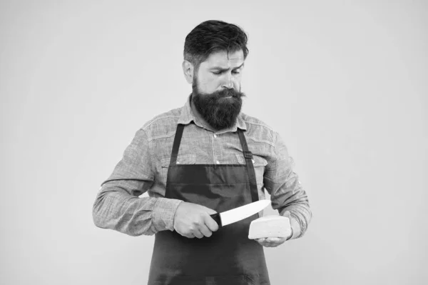 expertise cheese taste. ciet and nutrition. serious bearded man cut cheese with knife. cheesemaking concept. cheesemaker own business. hipster beard in chef apron. Dairy food shop. cheese festival