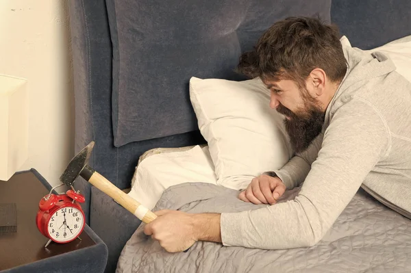 La vida cotidiana. Duerme más. Concepto de sueño saludable. El hombre barbudo hipster quiere dormir. Odio el ruido del despertador. Un tipo irritado destruye un reloj molesto. Hombre despierto infeliz con despertador sonando — Foto de Stock