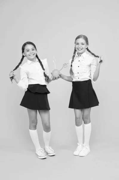 Iedereen houdt van een frisse kapsel. Kleine meisjes met lange kapsel drinken natuurlijk sap op gele achtergrond. Kleine kinderen met gevlochten kapsel genieten van Oranje drankje. Kapsel geschikt voor school — Stockfoto