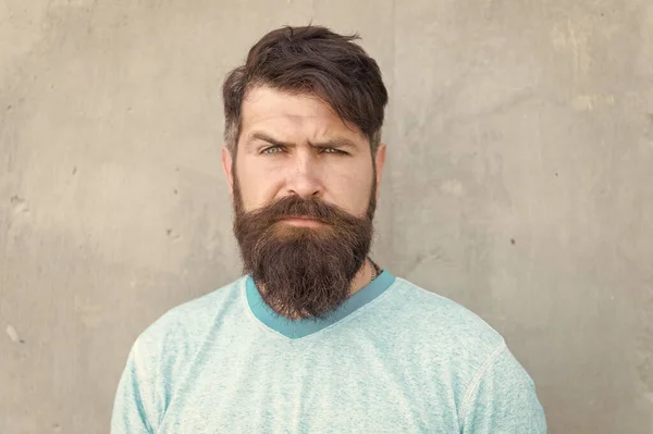 Zijn baard en kapsel zijn gestyled. Bearded Man dragen stijlvolle snor en baard vorm. Ongeschoren hipster met getextureerde baard haar op grijze muur. Serieuze blanke man met lange baard — Stockfoto