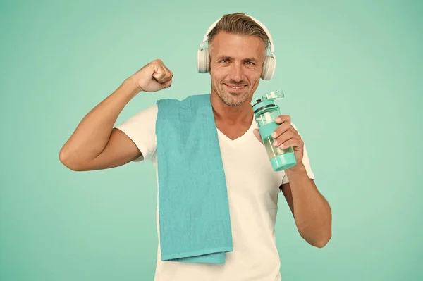 Sportsman promouvoir un mode de vie sain. Heureux sportif sur fond bleu. Ajustez sportif avec serviette. Beau sportif flex muscle du bras. Eau potable pendant l'entraînement. Entraînement avec écoute de musique — Photo