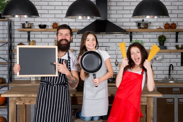 Birlikte yemek pişirmek. Tarif kopyalama alanı. Aile restoranı konsepti. En iyi yemek ekibi. Anne, baba ve kız önlükleri mutfakta. Öğle yemeği vakti. Aile birlikte yemek yaparken eğleniyor. Çocuklara yemek yapmayı öğret. — Stok fotoğraf