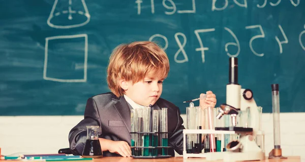 Ребенку нравится учиться. Концепция знаний. Мальчик возле микроскопа и пробирки в классе. Ребёнок изучает химию биологии. День знаний. Начальное образование начальной школы. Счастливого детства — стоковое фото