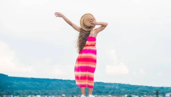 Helemaal gelukkig. Zomer kindermode. Klein meisje brengt tijd buiten door. bewolkt weer. Gelukkige kinderdag. zorgeloos kind in zomerjurk. klein meisje met lang krullend haar. kindergeluk — Stockfoto