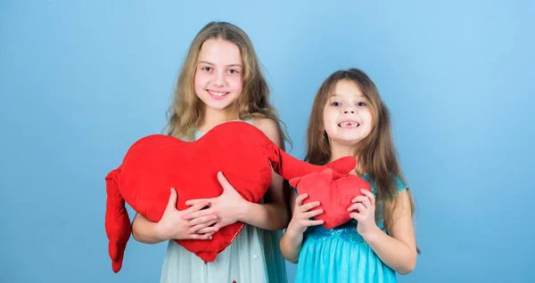 Girls hug red plush heart toy symbol love. Sisterhood concept. Valentines day. Friendly relations siblings. Family love. Happy feeling love. Loving sister. Sincere kids share tenderness and love