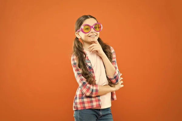 Pareja perfecta para una fiesta perfecta. Lindo niño pequeño mirando a través de gafas de fiesta con filtro de color. Adorable chica de fiesta con gafas de lujo. Chica de fiesta de moda sobre fondo naranja —  Fotos de Stock