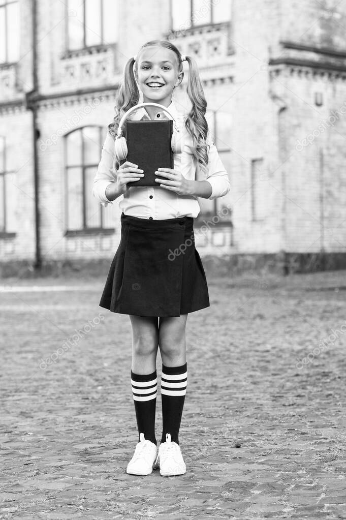 Knowledge assimilate better this way. Audio book concept. Listening school book. Digital technologies for learning. Elearning and modern methods. Girl cute schoolgirl hold book and headphones