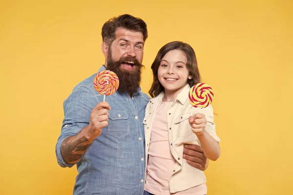 Voor jou. Dochter en vader eten zoete snoepjes. Een bebaarde hipster is een goede vader. Papa en klein meisje kind houden van kleurrijke lolly. Zomer vibes. Gelukkige familie rust. Gezondheidszorg. Zoete jeugd — Stockfoto