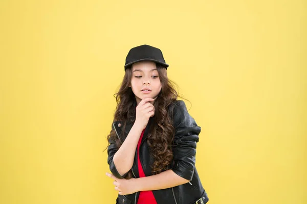 How to be a hipster. happy kid in stylish leather jacket. small girl just thinking. kid fashion concept. child has long curly hair. after visit to hairdresser. better look in cap. looking so cool — Stock Photo, Image