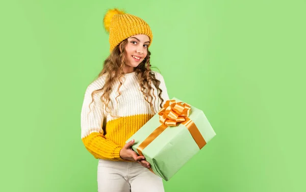 La Navidad es el momento de complacer. niña alegre sombrero de punto y suéter. niño mantenga presente caja pared verde. Feliz año nuevo. regalo de Navidad venta de compras. Feliz navidad para ti. descuentos de vacaciones de invierno —  Fotos de Stock