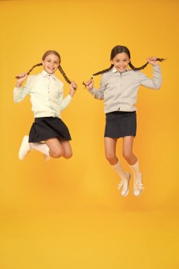 Bugün saç stilini güzelleştirmek. Sarı arka planda atlama uzun saç modeli ile sevimli küçük kızlar. Orta havada örgülü saç modeli tutan sevimli küçük çocuklar. Harika saç modeli her gün