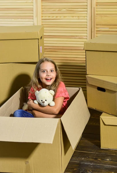 就在拐角处快乐的孩子纸板箱。移动的概念。新公寓。纸板箱-搬到新房子。快乐的小女孩带着玩具。购买新住宅 — 图库照片