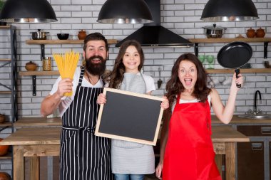 Lezzetli yemek tarifi. Evde sağlıklı yemek pişirmek. Anne babasıyla birlikte aşçı çocuk. Anne ve baba kızına yemek yapmayı öğretiyor. Mutlu aile günleri. Karşılıklı yardım. Mutfakta arkadaş canlısı bir aile. Boşluğu kopyala