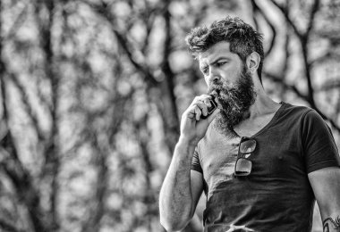 Uzun sakallı adam sigara içmekten rahatlamış. Sakallı ve bıyıklı adam duman üflüyor. Stres atma konsepti. Tüttüren sakallı adam. Beyaz aromalı duman bulutları. Elektronik sigara içiyorum.