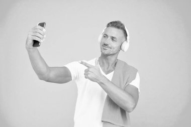 El resmi. Yakışıklı adam akıllı telefondaki selfie kamerasını işaret ediyor. Gülümseyen mutlu sporcu cep telefonuyla selfie çek. Eğitimden sonra selfie çekmenin tadını çıkarıyorum.