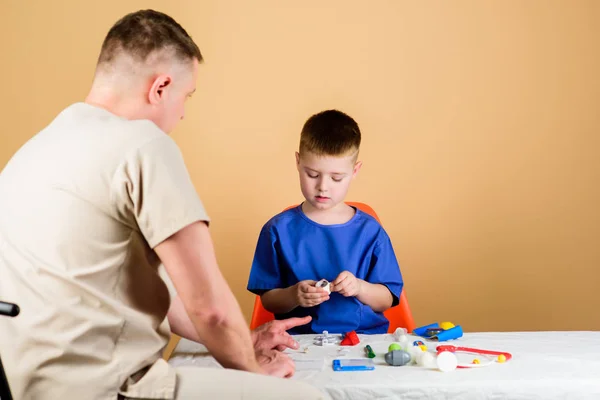 Servizio medico. Laboratorio di analisi. Il piccolo dottore si siede al tavolo degli attrezzi medici. Assistenza sanitaria. Concetto pediatrico. Visita medica. Ragazzo bambino carino e suo padre medico. Operaio ospedaliero — Foto Stock