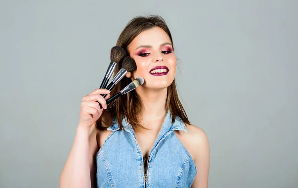 Kosmetikkonzept Make-up. Betonung der Weiblichkeit. Mädchen tragen Lidschatten auf. Hautpflege. Sieht gut aus und ist zuversichtlich. Frau schminkt Pinsel. Professionelles Make-up. Verschiedene Pinsel — Stockfoto