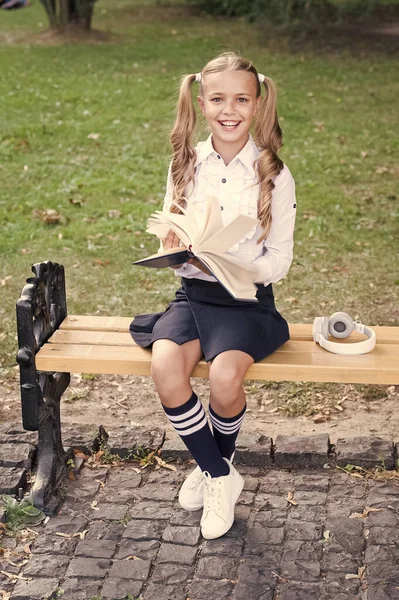 Hora de estudar. Estudante livro de leitura. Pequeno génio. Estudante relaxante sentar banco com livro. A estudar no pátio da escola. Uma estudante inteligente. Estudante adorável criança em uniforme formal relaxante ao ar livre — Fotografia de Stock