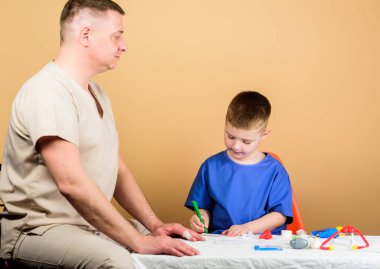 Babası steteskoplu mutlu bir çocuk. Baba oğul tıp üniforması giyiyorlar. Aile doktoru. Güven ve değerler. Babası hastanede olan küçük bir çocuk. İlaç ve sağlık. Mutlu çocuk babayla oynuyor.