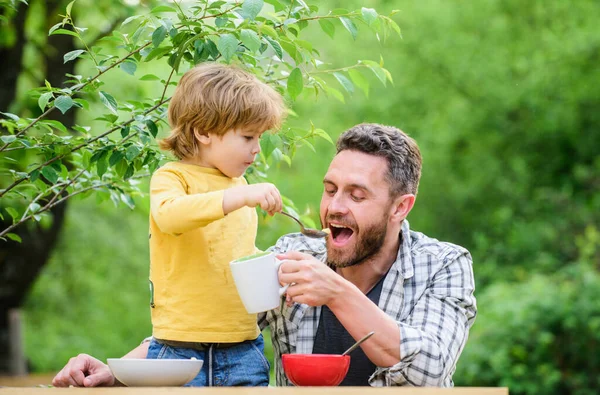Menu for children. Family enjoy homemade meal. Food habits. Little boy with dad eating food nature background. Summer breakfast. Healthy food concept. Father son eat food and have fun. Feeding baby — Stock Photo, Image