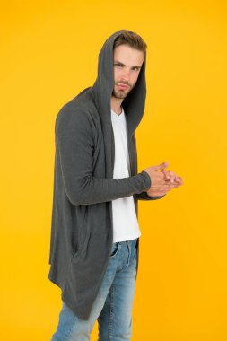 Sıradan, gayretsiz bir tarz. Şık bir adam şık bir kapüşonlu giyer. Yakışıklı adam sarı arka plan. Moda ve tarz. Günlük kıyafet ya da spor giysi. Koruyucu dış giysi. Rahat ve sıcak. Günlük biçim