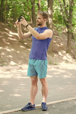 Uygulamayı kullanarak rota çalıştır'ı oluşturun. Adam akıllı telefon koşuya başlamaya hazır. Uygulamayı ayarlayın. Akıllı telefon ve akıllı saatli sporcu koşuya hazırlanın. Spor uygulaması ile eğitim daha eğlenceli