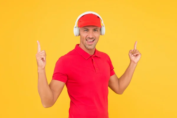 Guy call service worker. Man listen music headphones. Audio guide. Man in headphones on yellow background. Incoming call. Worker in uniform with earphones. Assistant call center help find solution — Stock Photo, Image