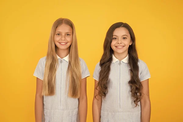 Niños felices con el pelo largo. moda y belleza. felicidad infantil. cabello sano. Niña con uniforme escolar. Mirada retro. hermanas en vestido vintage. la vieja escuela. Moda infantil. morena y rubia —  Fotos de Stock