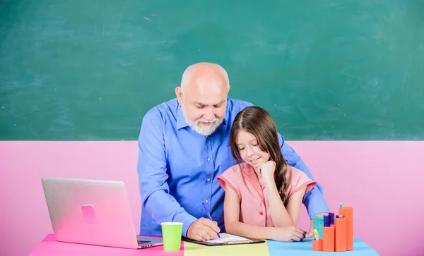 Vang me op mijn best. De lerares helpt schoolmeisje. online onderwijs. Terug naar school. klein meisje met man studie op laptop. online winkelen op school. Ik schrijf een opstel. moderne technologie in het leren — Stockfoto