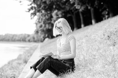 Kız nehir kenarında yeşil çimenler üzerinde otur. Kız iş gününden sonra nehir kenarında diniyor. Tatil in hayalini kuranan kadın. Dinlenin ve hobi edin. Kendiniz için boş zaman geçirin. Tatil sezonu. Yaz tatili