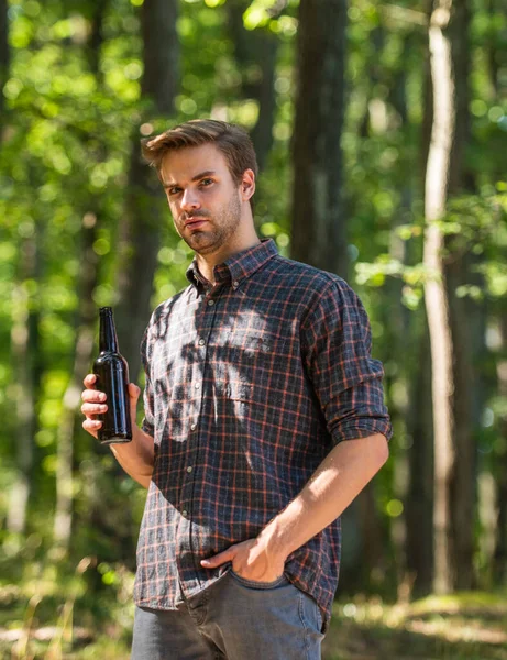 El hombre bebe cerveza en el bosque. relajarse en fin de semana de picnic de verano. temporada de camping comenzar. le encanta hacer senderismo. concepto de aventura turística. beber cerveza en el camping. no dejes basura en el bosque. contaminación ecológica —  Fotos de Stock