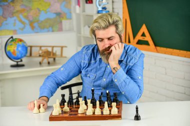 Bir sonraki hamleyi düşünüyorum. Satranç yarışması için sakallı adam eğitimi. Tahta üzerinde satranç figürleri. Odaklanmış öğretmen. Rakip satranç taşlarına saldırmayı ve onları yakalamayı düşünüyor.