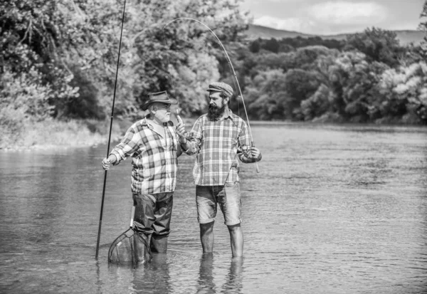 fishing Still Keeps Us Together. hobby and sport activity. Trout bait. two happy fisherman with fishing rods. male friendship. family bonding. father and son fishing. summer weekend. men fisher