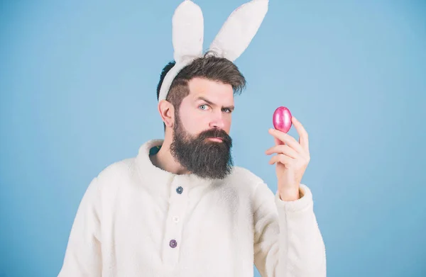 Πασχαλινό. Hipster φορώντας μακριά αυτιά κουνελιού με πασχαλινό αυγό. Το πασχαλινό αυγό είναι σύμβολο της νέας ζωής και της ανάστασης. Γενειοφόρος με στολή πασχαλινού κουνελιού που κρατάει αυγό πασάλ. Παράδοση χρωματιστών αυγών — Φωτογραφία Αρχείου