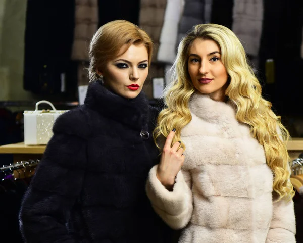 Girls with confident faces hold furry coats — Stock Photo, Image